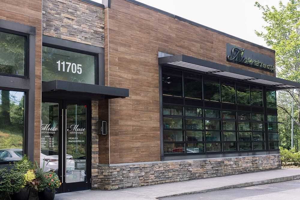 Exterior view of a modern building with large windows and a stone accent wall.