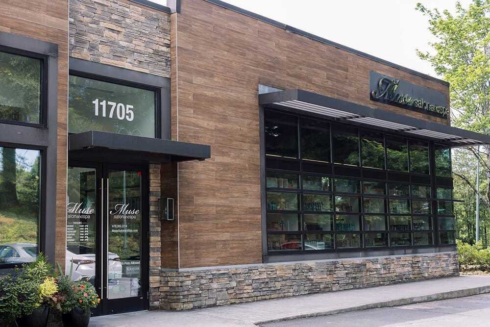 Exterior view of a modern building with large windows and a stone accent wall.