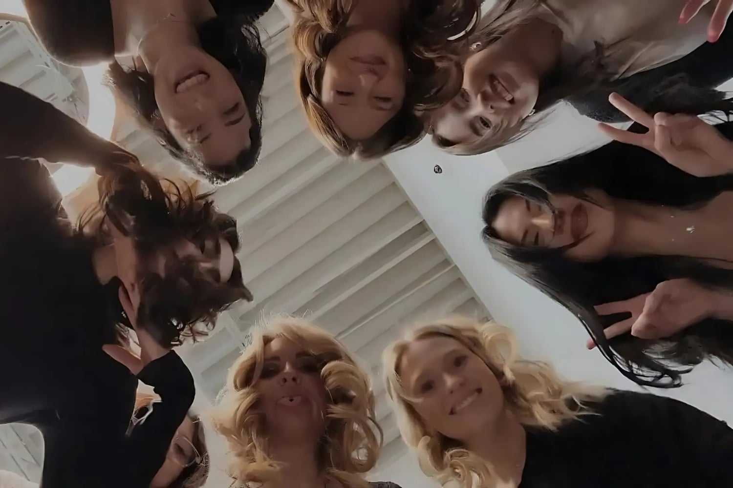Group of friends in a circle, smiling down at camera.